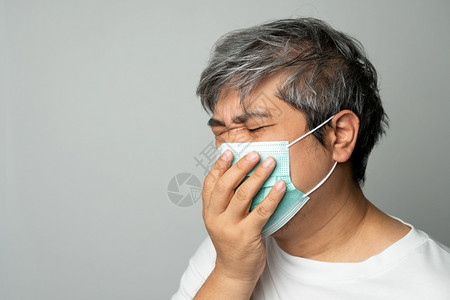 戴医疗口罩的咳嗽的中年男性图片