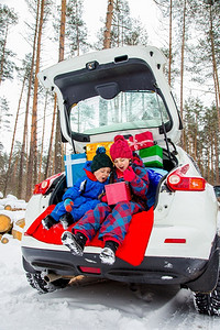 摩托车尾箱汽车快乐的孩子享受许多圣诞礼物在车尾箱里寒冷的冬天雪气快乐的孩子享受许多圣诞礼物在车尾箱里假期乐趣背景