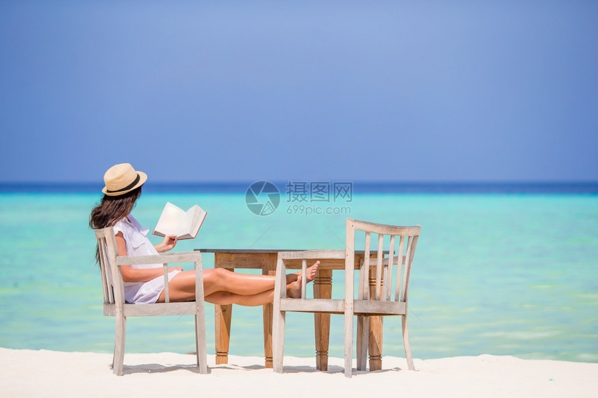 白沙滩上阅读的年轻妇女图片