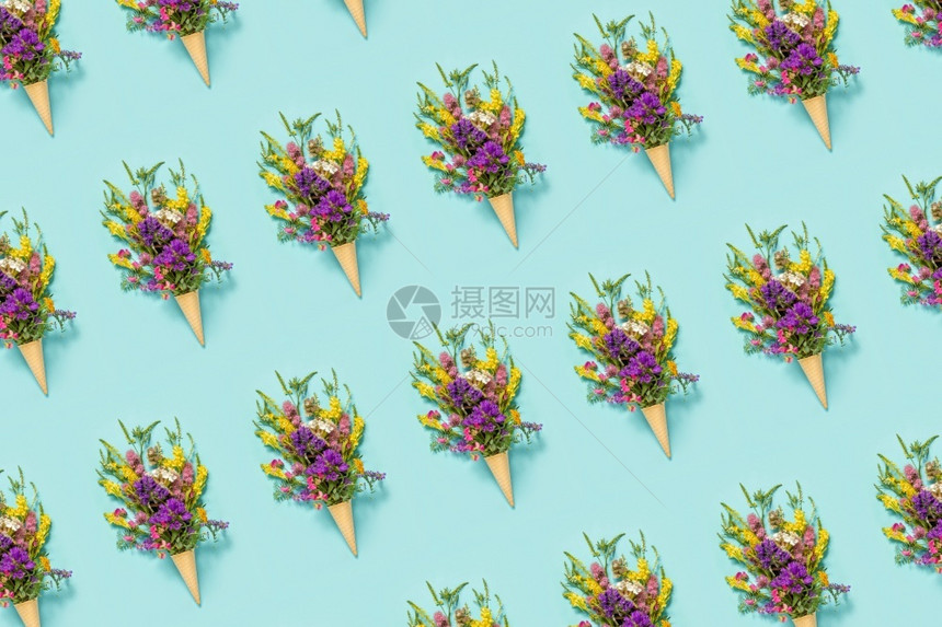 有创造力的春天母亲花卉图案束领域彩色朵在蓝纸背景的华夫饼冰淇淋锥创意平躺顶视图花卉案束领域彩色鲜在华夫饼冰淇淋锥在蓝纸背景图片