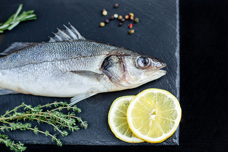 吃低音黑石板上的生鱼鲈配香料和草新鲜的鲈鱼顶视图带复制空间美食图片