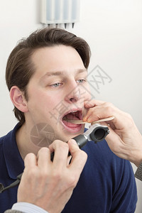 耳鼻喉科年轻男病人接受医生检查其舌和嘴口以确诊感染技能疮背景图片