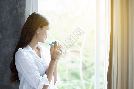 早晨漂亮的吸引人亚裔妇女喝咖啡在床上醒来后完全休息清晨打开窗帘以获得阳光的新鲜空气亚洲妇女喝咖啡在床上醒来背景图片