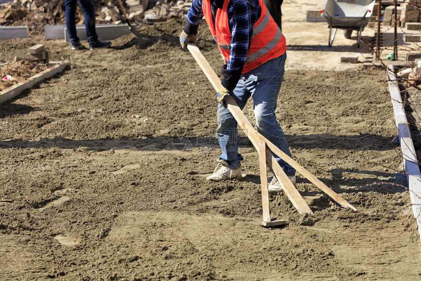 对齐街道工人将地基与木制层接轨开始在工作区铺设布的板块工人将地基与木制层接轨以便在人行道上对建筑工地铺砖措施图片