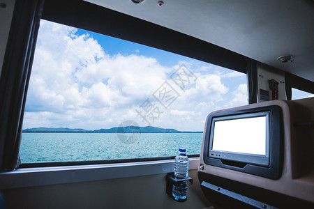 城市的巴士内有液晶屏幕用瓶水和窗外风景美丽的自然观娱乐用LCD空白后座娱乐用的LCD屏盘其中含有天空云的海洋图旅游公路行概念广告背景