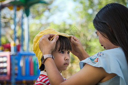 情感年幼母亲在暑假公园给女儿戴帽子家人一起渡过假期的家事摆姿势女孩图片