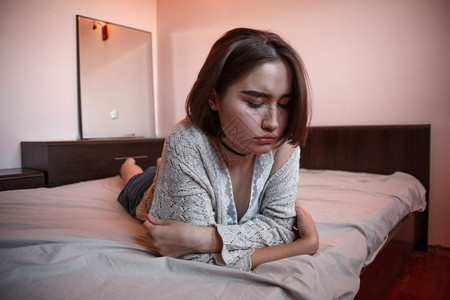 穿着毛衣短发的年轻女孩戴尼姆裙子单独躺在卧室的床上焦虑情感疲劳图片