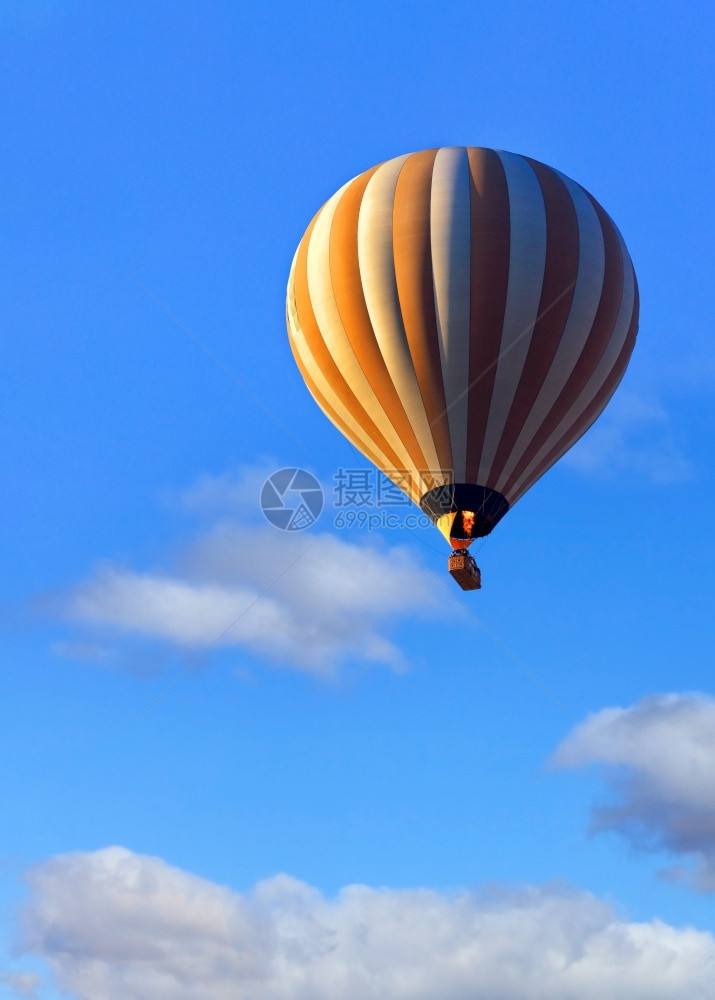 太阳光照耀的体积气球将一篮子举起游客高飞向天空火的焰以气球垂直图像闭合式复制空间的形式点燃气飞行美丽的热气球与蓝天上的一篮游客起图片