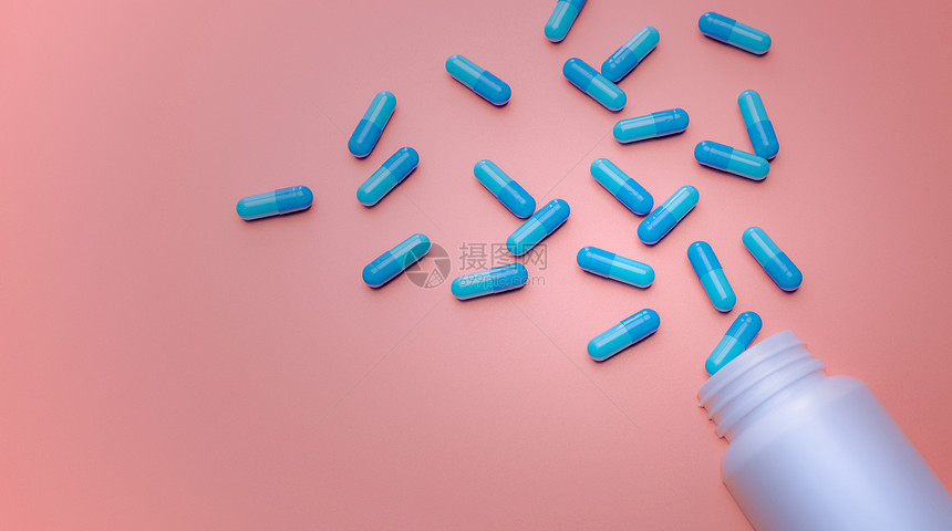 助推器白塑料药瓶在粉红背景用旗条上散布的蓝色胶囊药丸分布在粉红底上的白塑料药瓶网店止痛品和抗生素物概念白色的粉彩图片