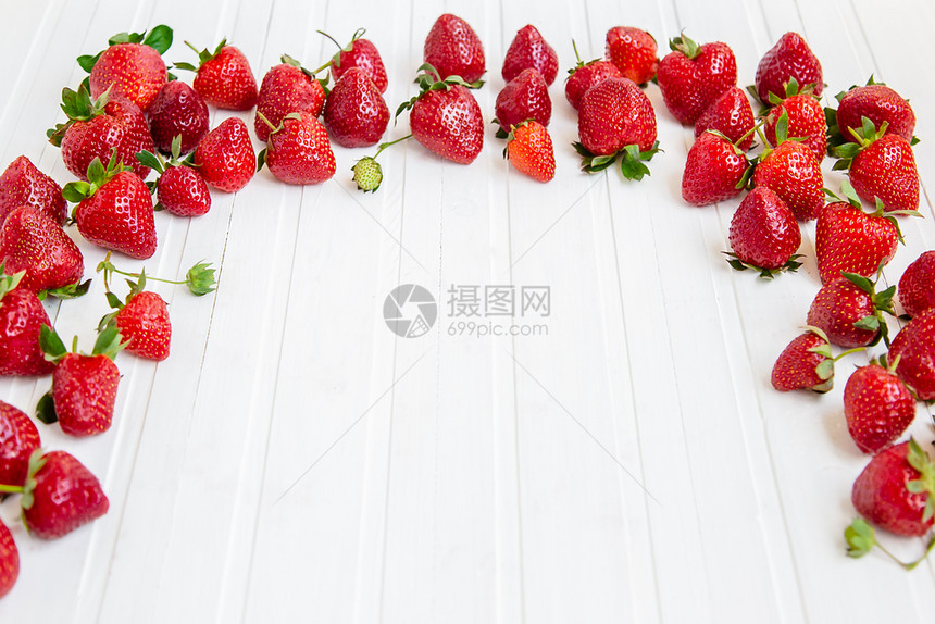 成熟的红草莓散落在白色的木桌上背景有草莓文本的地方背景有草莓盘子团体营养图片