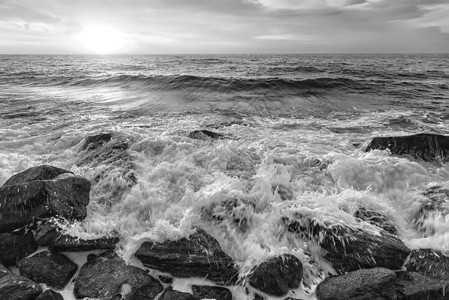 流动的日出模糊在黑海岩石岸的天空和水泡沫下惊人的黑白海景与乌蓝图片
