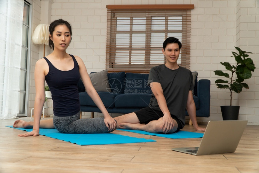 正在做力量健康的年轻亚洲夫妇有吸引力的情侣在网上家庭隔离课坐在一张垫子上进行瑜伽练习这是家用新正常生活方式技术概念的一个在线隔离图片