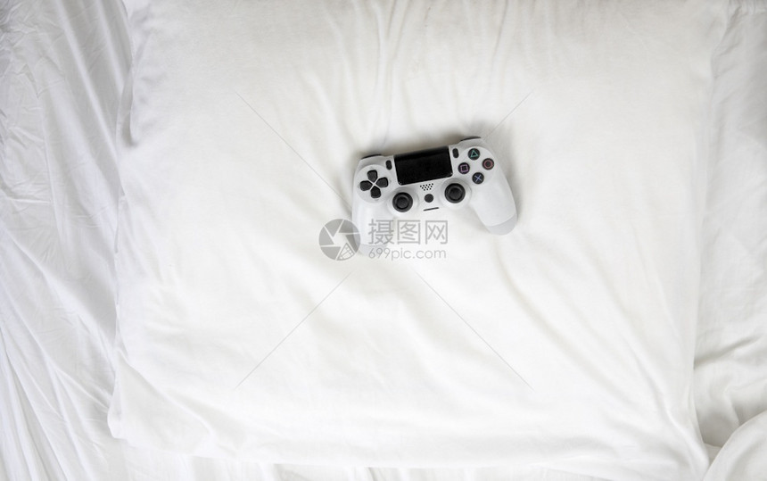 玩人们关闭图像顶端视游戏控制器躺在家中带复制空间的白床单上图片