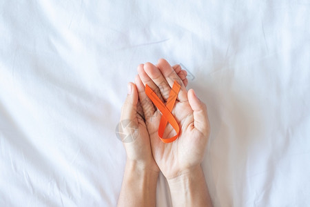 手拿橙色丝带预防癌症概念背景图片