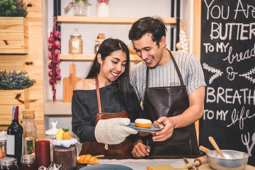 家庭食物商业年轻夫妇在面包店做甜圈和作为企业所有权家夫妻在厨房一起做饭幸福人和生活方式关系概念图片