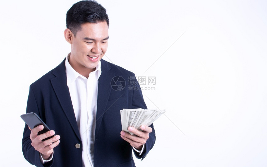 套装成就亚洲商人身穿西装使用手机带着微笑的脸和站在白色背景上拿着钱与面带笑脸庆祝图片
