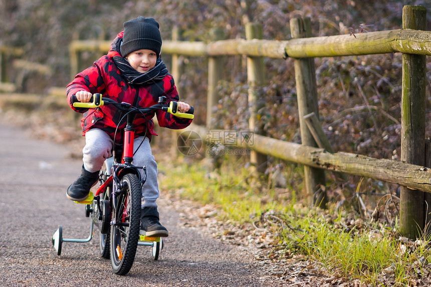 闲暇学前班冬季男孩在公园骑自行车时开心的快乐小男孩图片