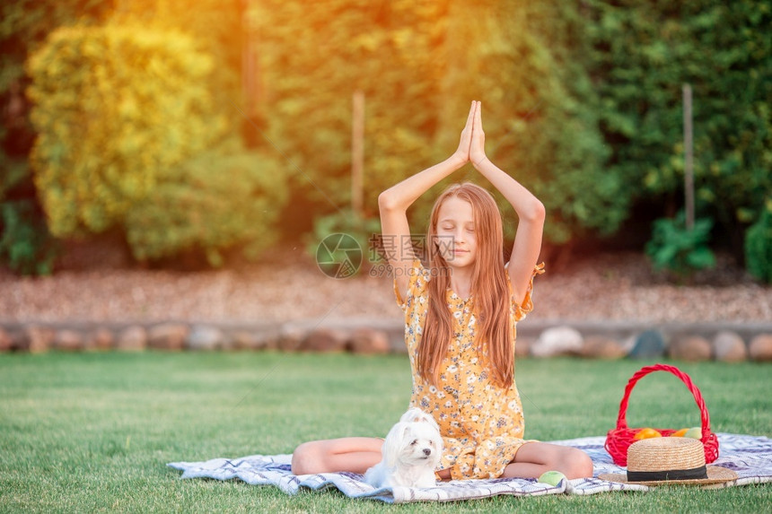 沉思一种美丽的小女孩在公园野餐上穿着瑜伽姿势冥想坐在公园的瑜伽姿势脚图片