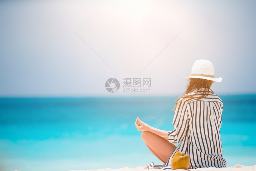 白色的水在沙热带海滩上做瑜伽的年轻美女在海滩上穿绿礼服的年轻时尚女郎采取图片