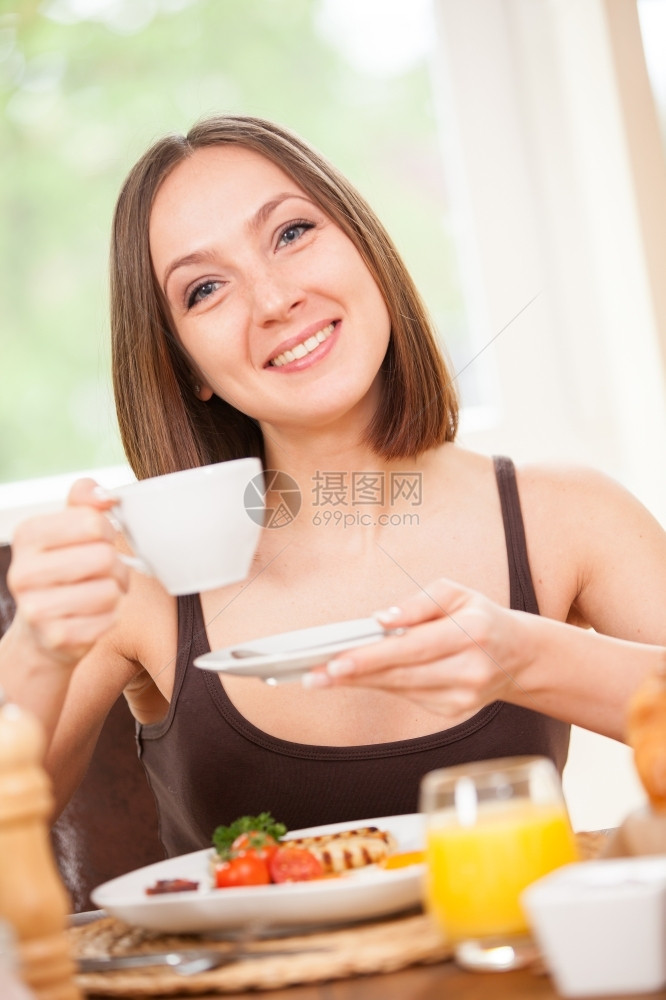 合身轻松国内的年女子在家吃早餐时喝着热咖啡图片