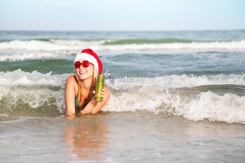 享受海洋浪潮的快乐妇女克里斯蒂玛集圣诞节老人鸡尾酒图片