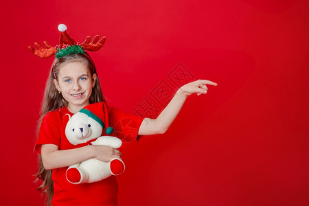 广告熊素材美丽的快乐拥抱一个有趣快乐女孩肖像头上缠着角绷带抱一只泰迪熊穿着圣诞睡衣背景为鲜红色头抱着一只泰迪熊与鲜红色背景隔开背景