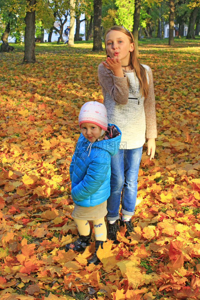 好的在秋公园黄叶上玩秋公园的黄色树叶上玩Childs假扮成前摄像头秋森林的小女孩秋森林的季情调散步快乐童年姐妹们在秋公园的黄色树图片