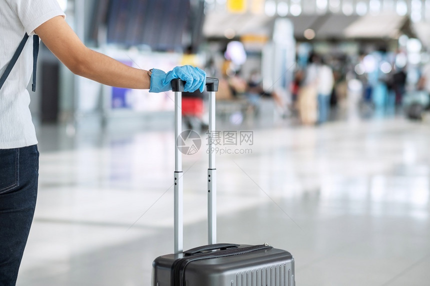 戴手套在机场候托运行李箱的游客图片