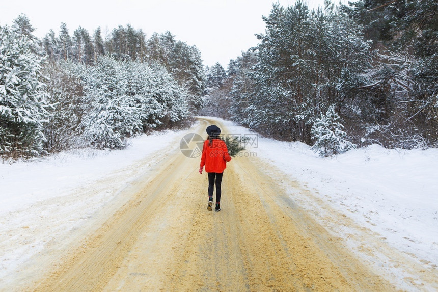 乐趣季节时尚一个穿着红色毛衣和帽子的女孩站在雪道中间松枝的森林里周末旅行穿着红色毛衣和帽子的女孩站在雪道中间松枝的森林里图片