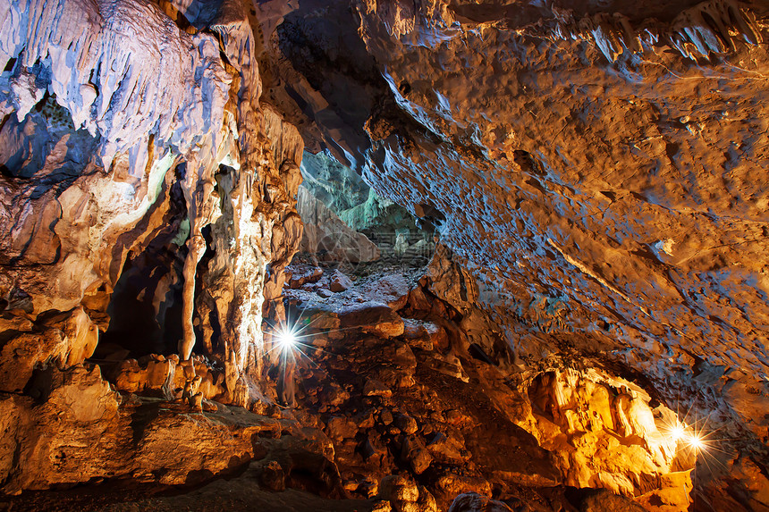 墙形成粗糙的利用火炬魔法形状和泰国南瑙家公园大洞穴内石状物和stalagmites的纹理用火炬神奇形状和纹理探索神秘的石灰岩洞穴图片