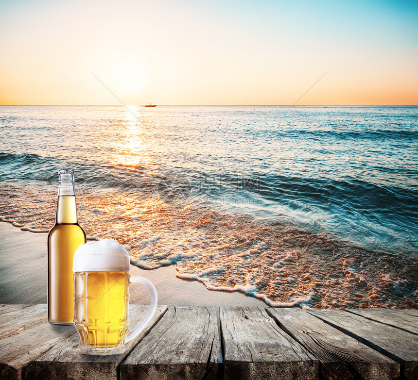 蓝色的桌子上杯和一瓶啤酒靠海桌子上的杯和一瓶啤酒城市的景观图片