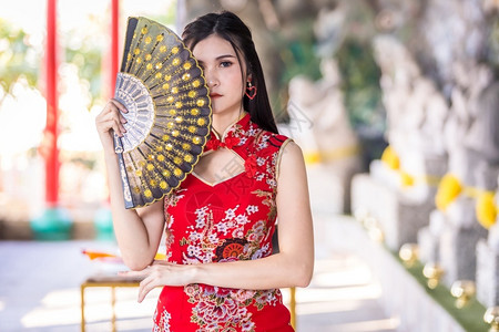 时尚风向毛笔字戏服肖像亚洲年轻女子身着传统红青山装饰在泰国华神庙举办中新年节盛会的风向节日活动校对Portnoy黑色的背景