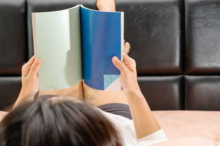 亚洲快乐的女士躺在床上阅读书本复制空间家常枕头图片