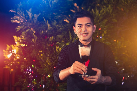 亚洲男青年酒保在户外夜总会将酒精饮料鸡尾混合到玻璃中人民生活方式与职业就和概念圣诞节和新年活动主题圣诞和新年活动节夜店生晚背景图片