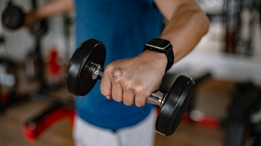背部运动员训练体操概念一个年轻的成人用他肌肉强壮手臂在健身房上下举起一个哑铃重图片
