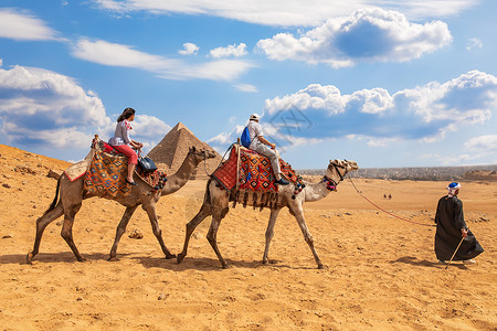 开罗埃及废墟吉扎金字塔附近骑骆驼的旅游者在吉扎金字塔附近骑骆驼背景图片