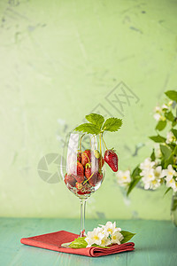 新鲜成熟的生草莓在绿面红酒杯中含色叶子新鲜的奶油多汁图片