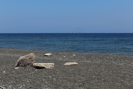 希腊圣托里尼岛的卡马海滩带有黑色火山石水娱乐松弛图片