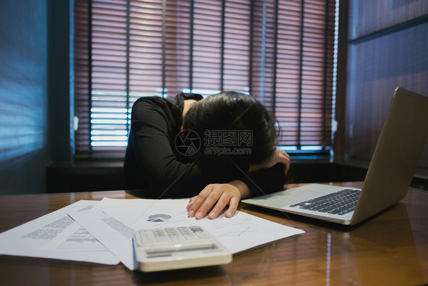 技术金融成人睡在办公室用笔记本电脑和有财务文件打盹的疲累商业妇女图片