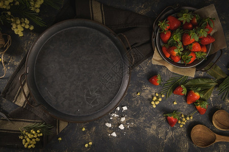 蛋糕黑色背景的新鲜草莓和圆金属板面粉末花朵一种图片