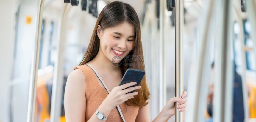 目的地商业人使用智能手机的亚洲年轻女乘客在大城市通勤和交中旅行时寻找地铁列车外的坐客概念在大型城市上下班者和运输方面图片