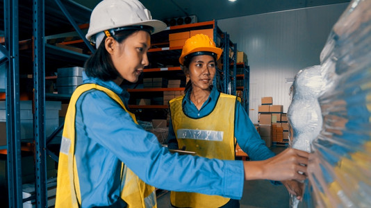 在仓库工作的女人物流供应链和仓库业务概念在仓库工作的女人货运盒子背心图片