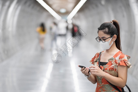 在地铁戴口罩拿手机的女士图片