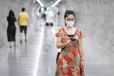 地铁站戴口罩拿手机的女士图片