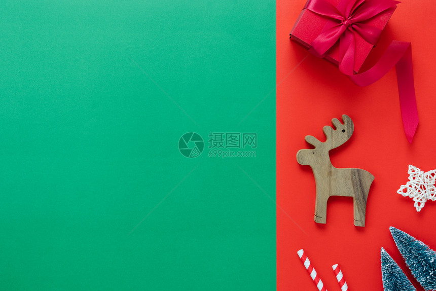 木头欢乐新年装饰品概念Flat在家庭工作室办公桌红绿纸背景的木制驯鹿礼品盒上写着基本物品Flat为这些必要物品铺设了木制驯鹿礼品图片