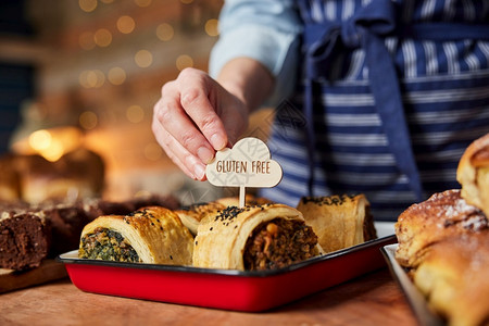 销售助理在面包店放Gluten免费标签到新鲜烘烤香味卷推杆有机的小吃图片
