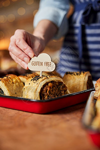 工匠店铺烘烤的销售助理在面包店放Gluten免费标签到新鲜烘烤香味卷图片