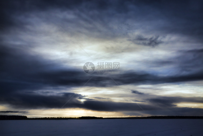 冬季风景日落时有雪和天空覆盖的田地严冬风景以黄色日落太阳照亮黑乌云经过天气冰图片
