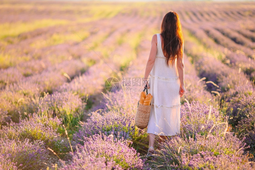 香气人们穿紫花衣的年轻美女穿着白裙子和帽日落时戴白帽子的紫花朵图片