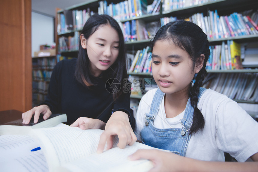 两个女学生在图书馆阅读笔记本图片